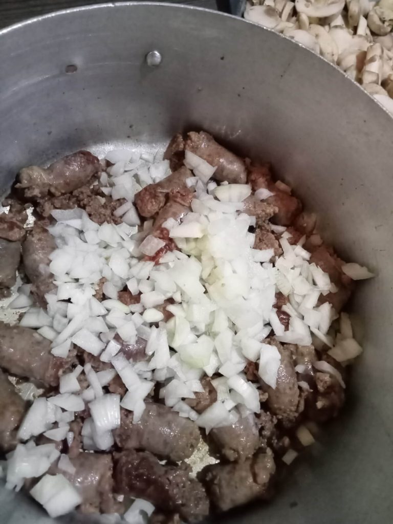 ground sausage with diced onion in a saucepan