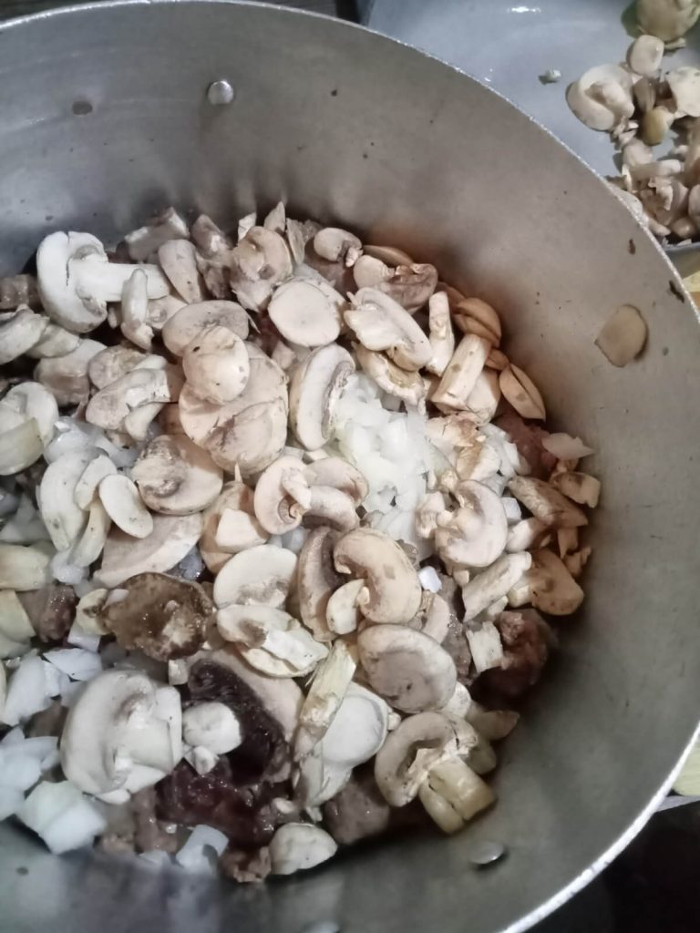 ground sausage with diced onion & mushrooms in a saucepan