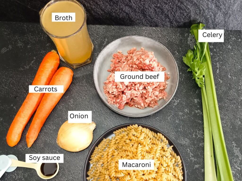 Ingredients shots, there is carrots, onion, broth in a cup, ground beef in bowl, celery stick, macaroni, and soy sauce.