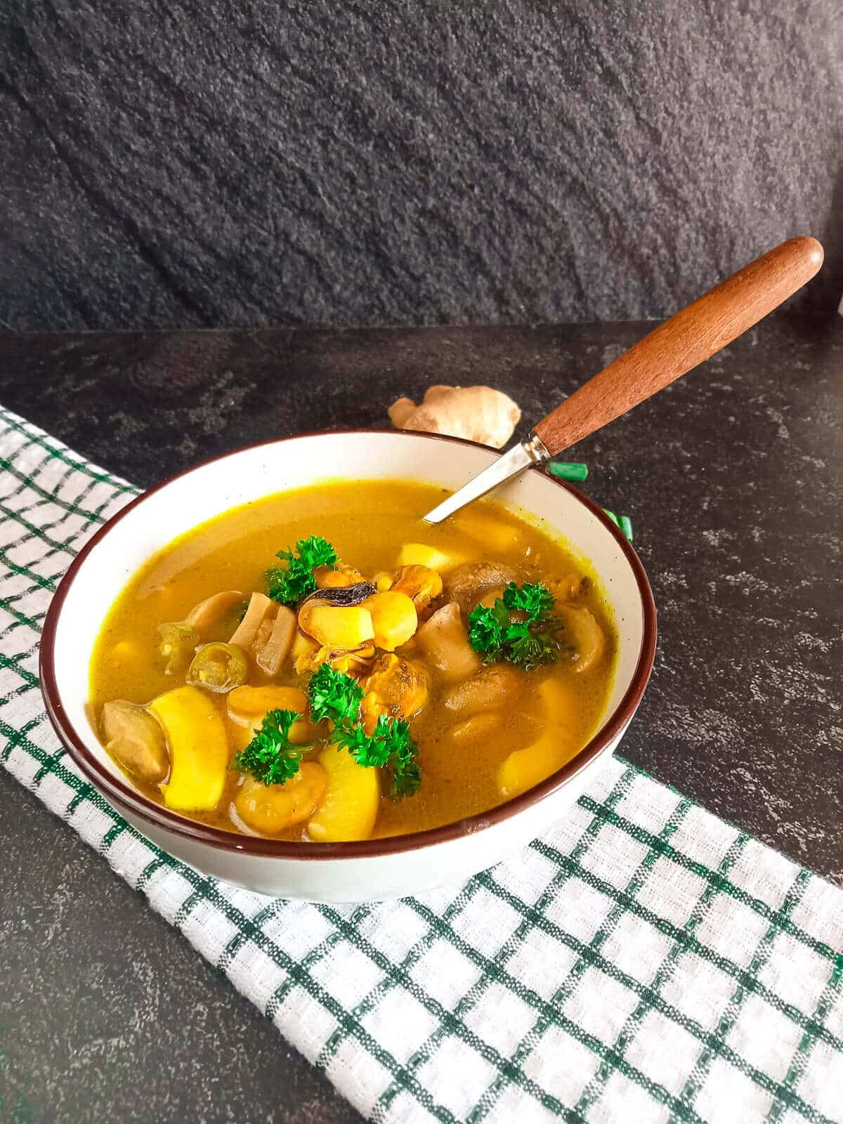 poh tak soup scooped with silver and wooden end spoon.