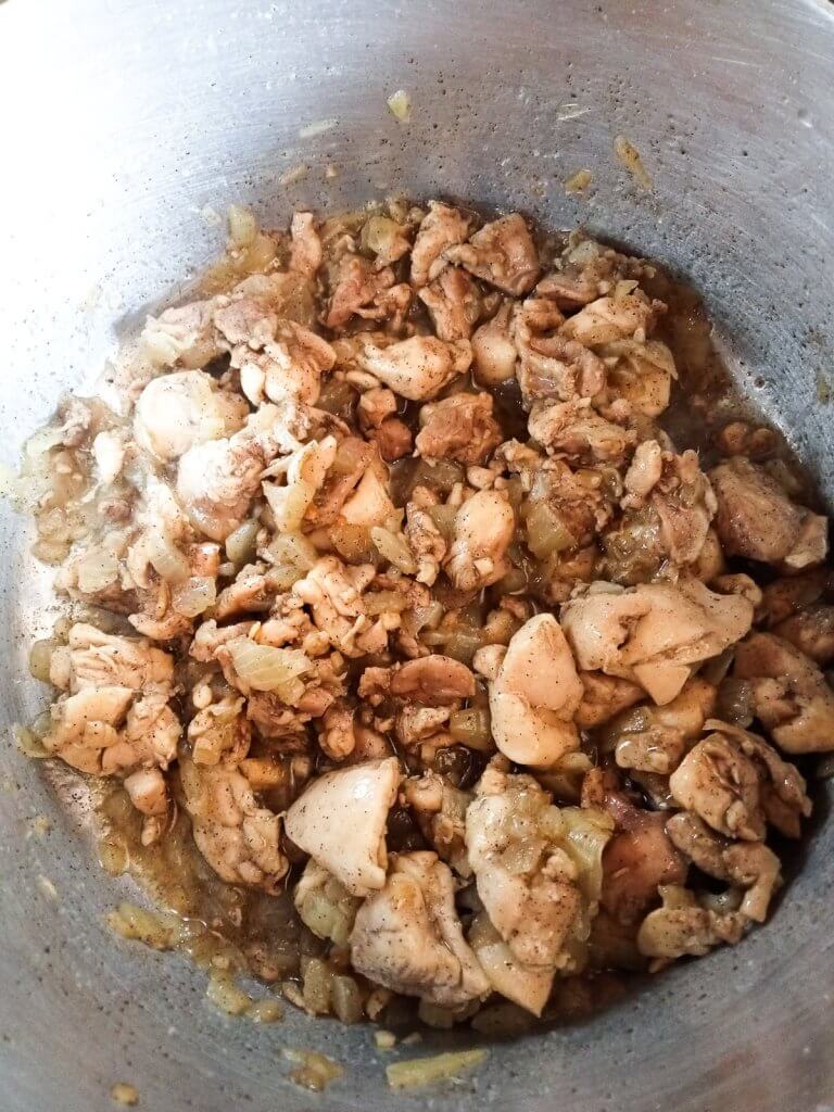 bite-size chicken pieces in a pot cooked with onions and minced garlic.