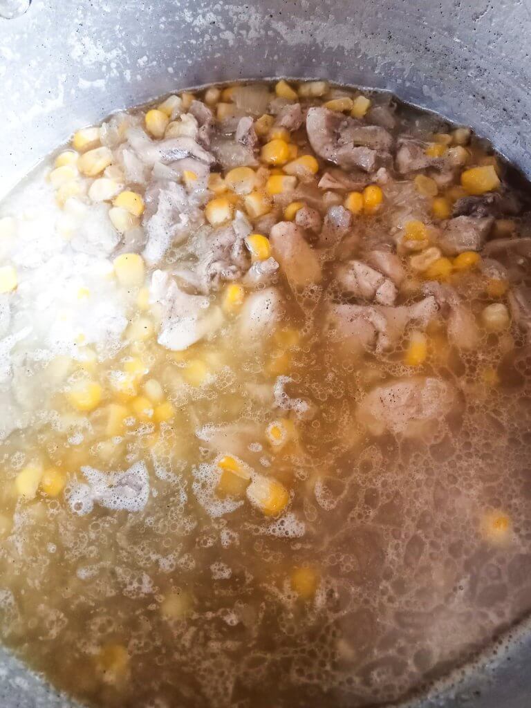 a process photo showing the step where corn and chicken broth are added into a pot.