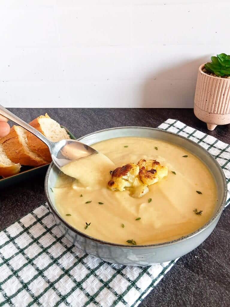 scooping cauliflower soup from a bowl with a spoon