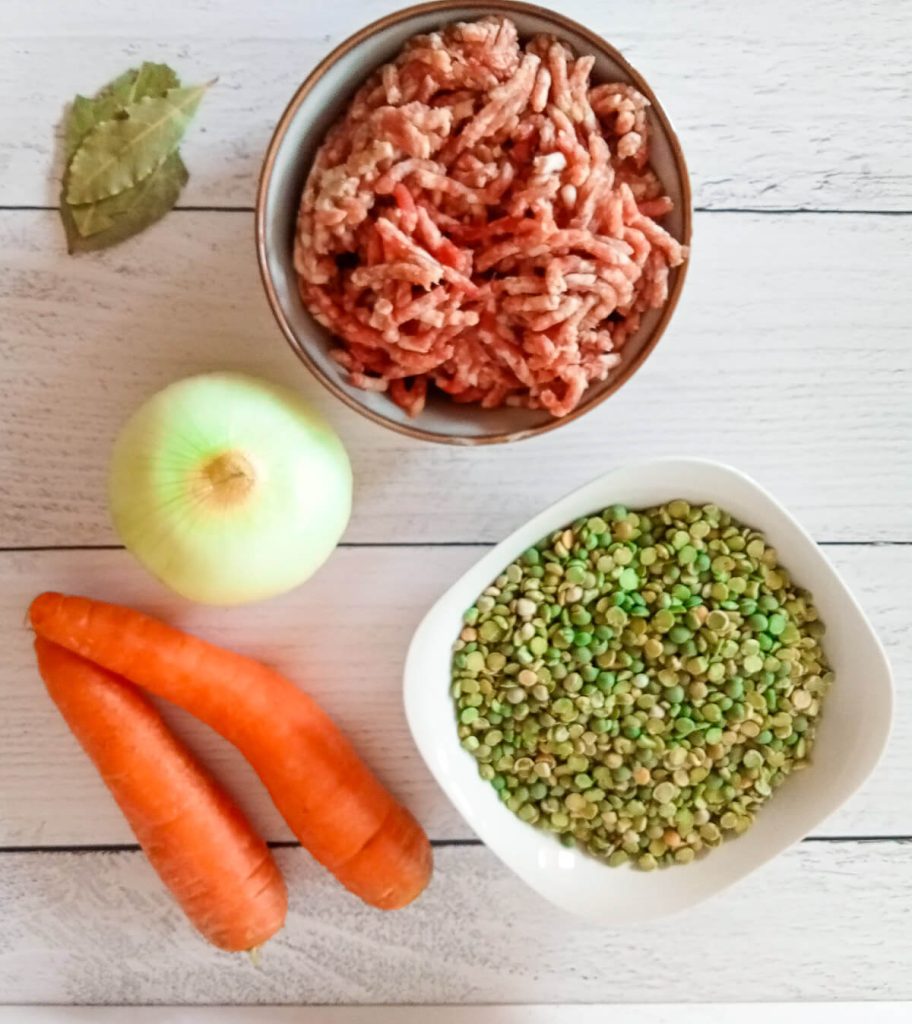 An ingredients photo, on it there is 2 small carrots, green split peas, onion, bay leaves and ground beef.