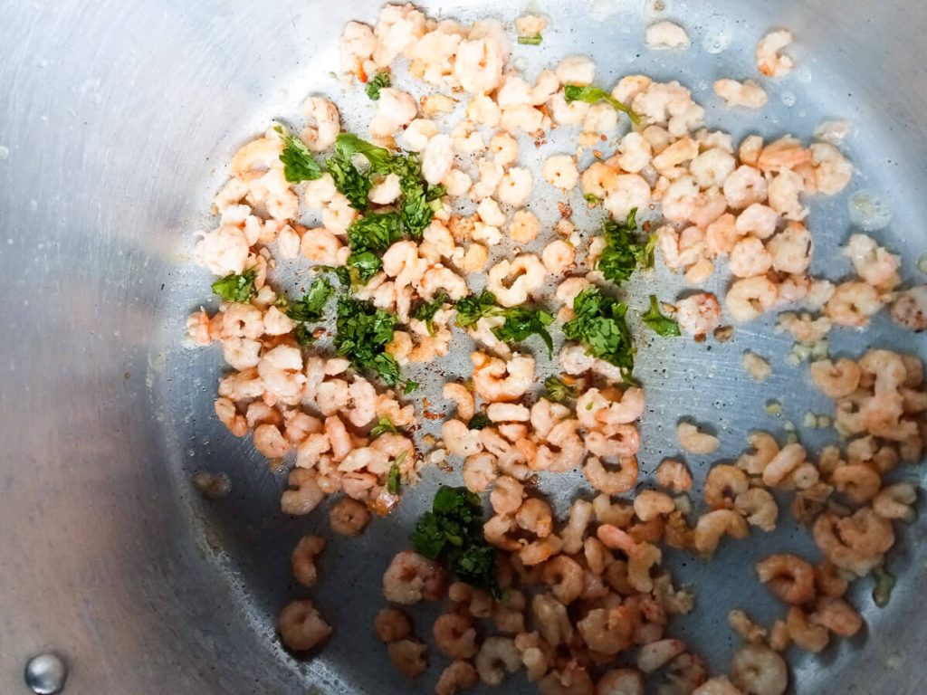 a photo of a pot with shrimp, coriander and minced garlic in it