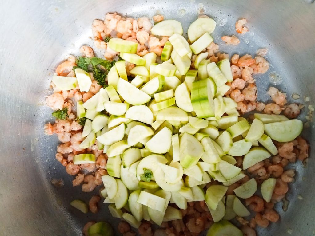 a photo of a pot with shrimp, coriander, opo squash and minced garlic in it