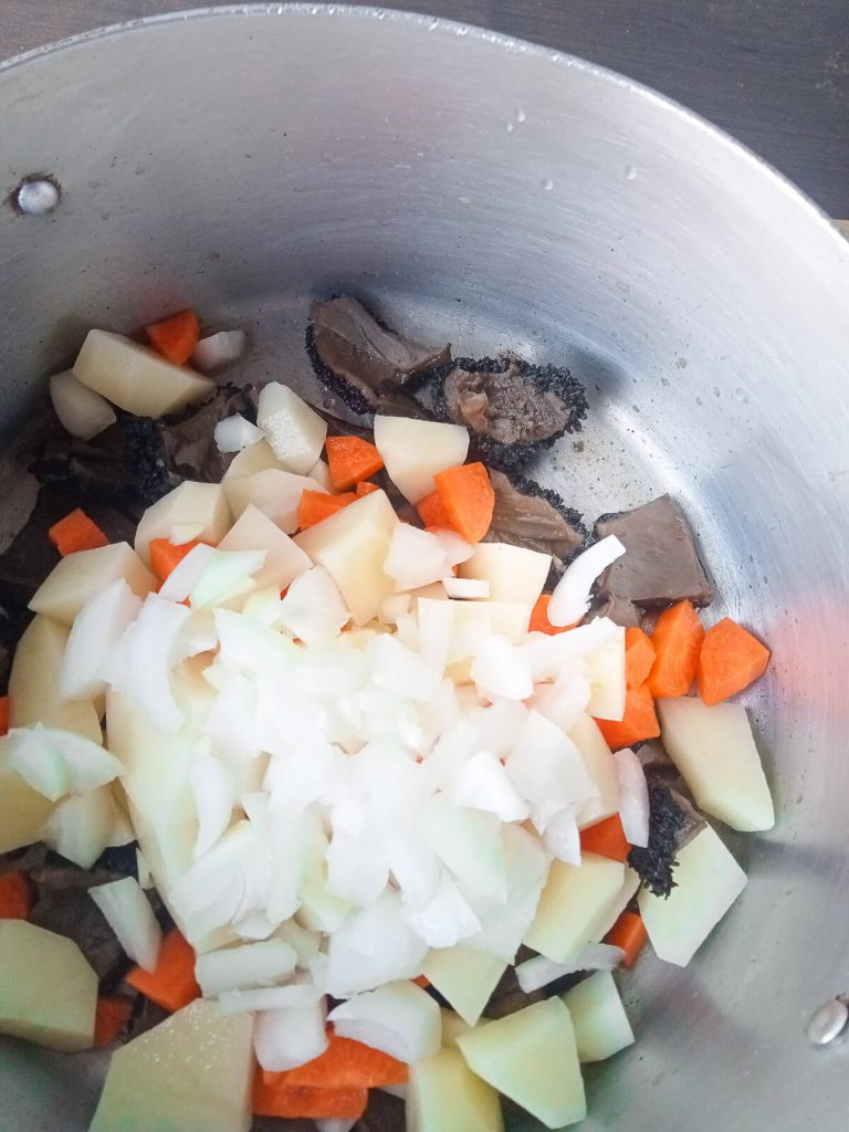 process photo- adding vegetables to the pot of beef tribe