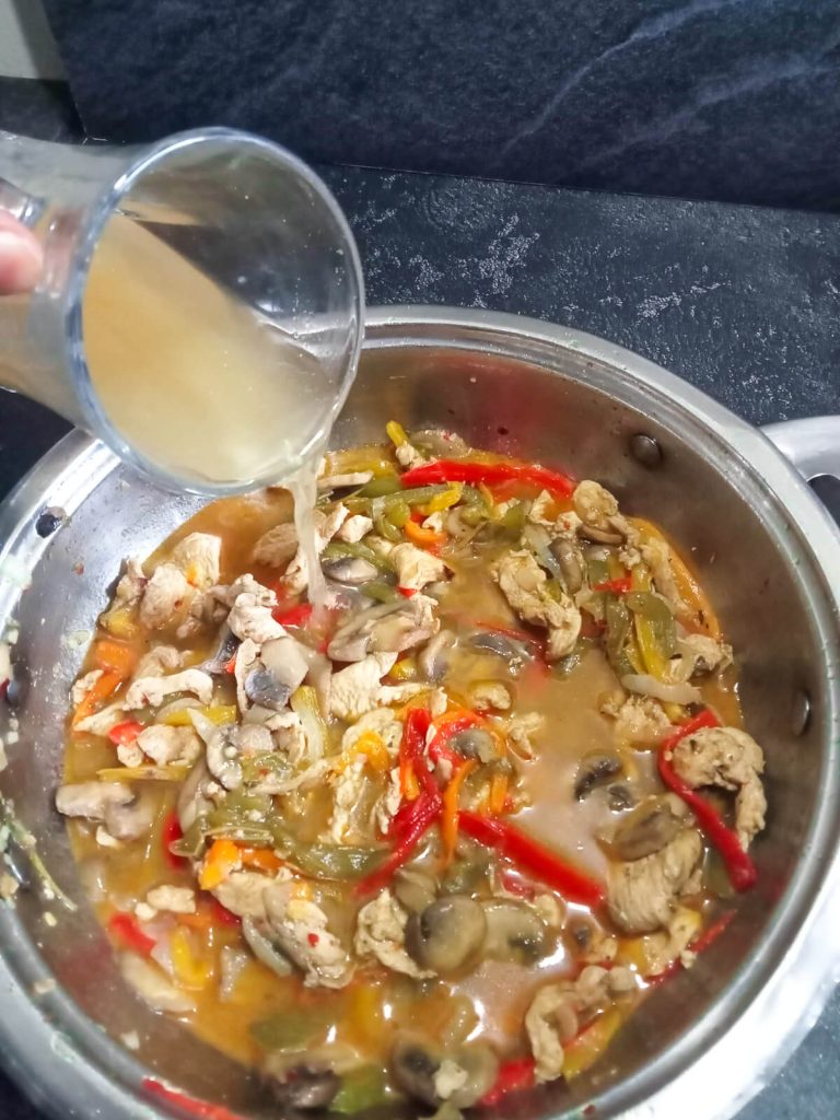 process photo- a cup of chicken broth added to the stir fry vegetables and chicken.