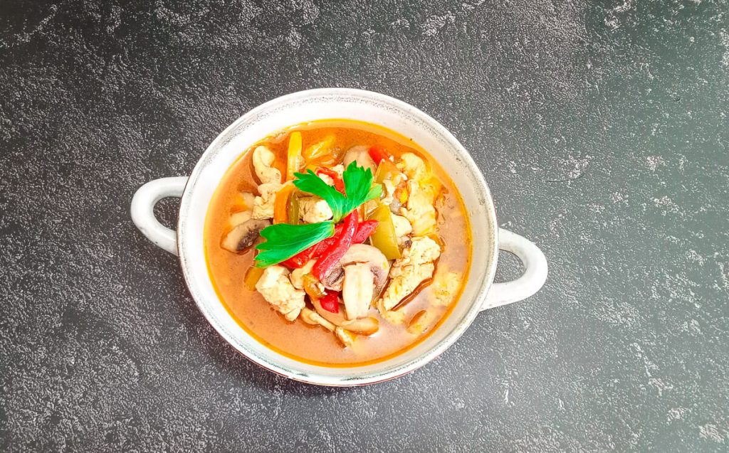 an overheads shot of a bowl of stir fry soup on a black background.