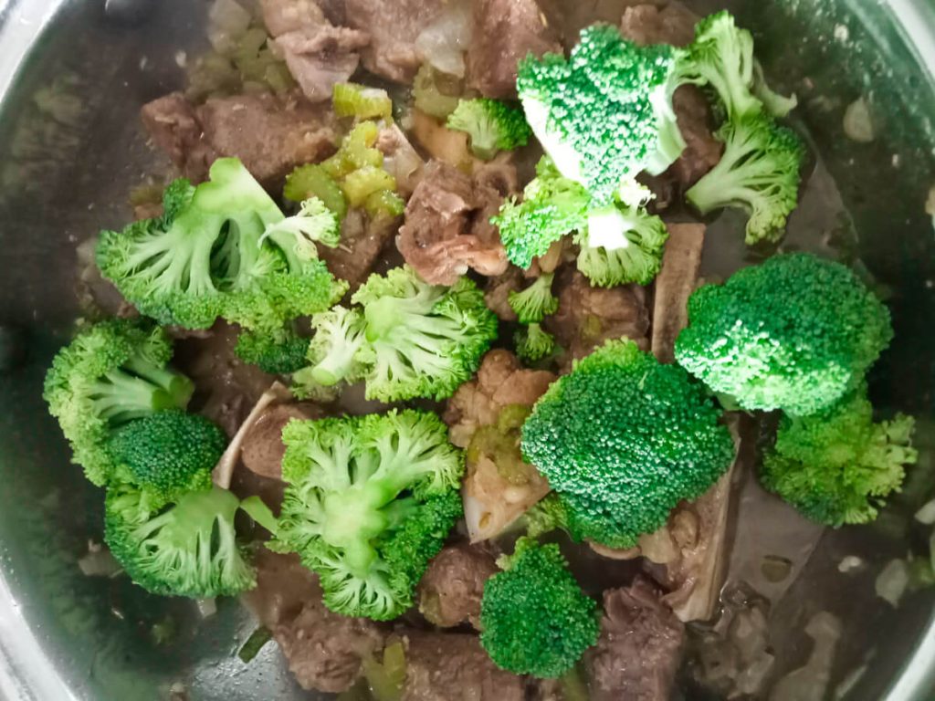 Process photo: broccoli florets added to the pot of beef and broth.