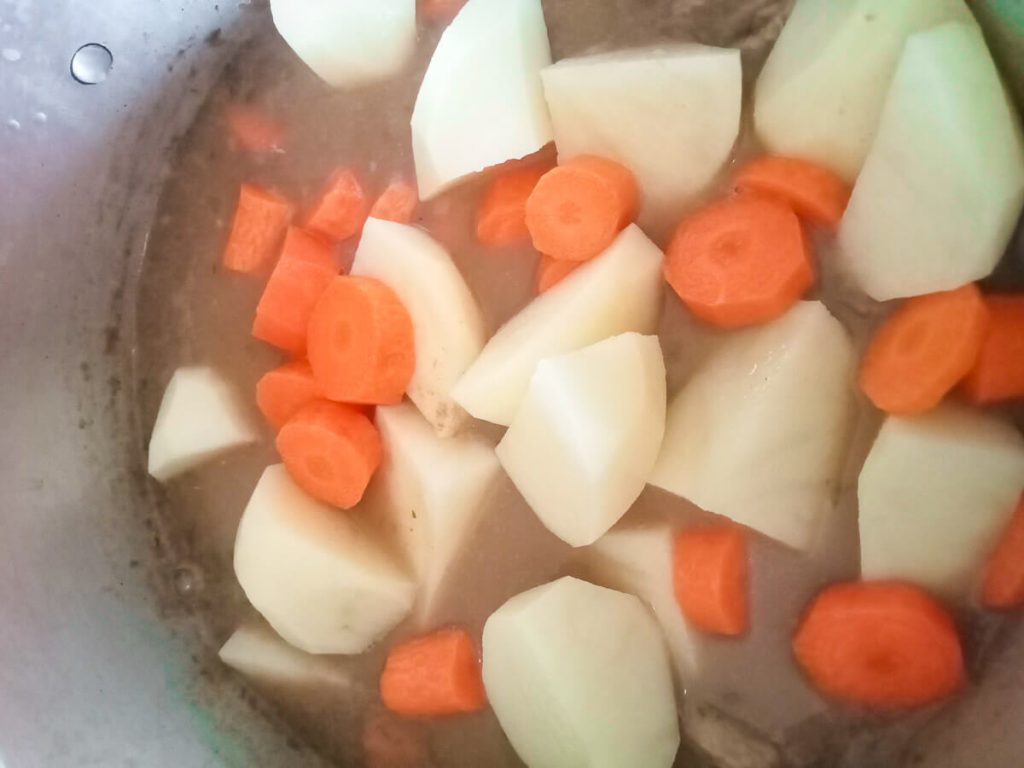 process shot: adding carrots and potatoes to the red pea soup pot.