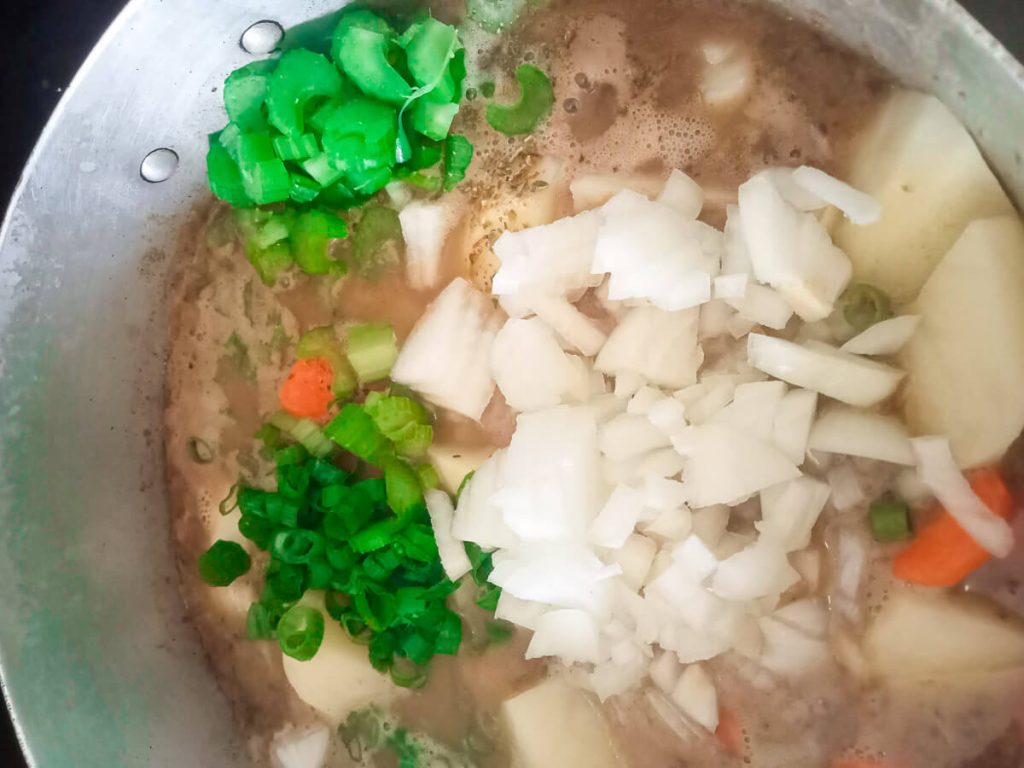 process shot: adding chopped onions and celery to the soup.