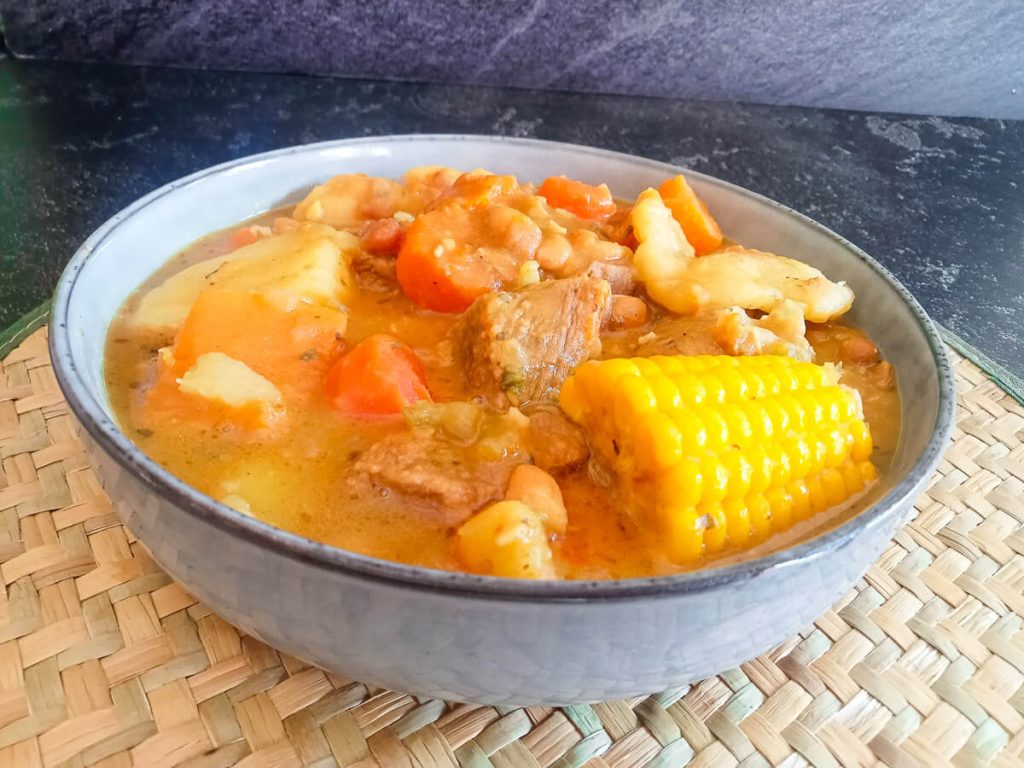 a close-up shot of a Jamaican red pea soup bowl on a plate mat with a black background.