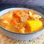 a close-up shot of a Jamaican red pea soup bowl on a plate mat with a black background.