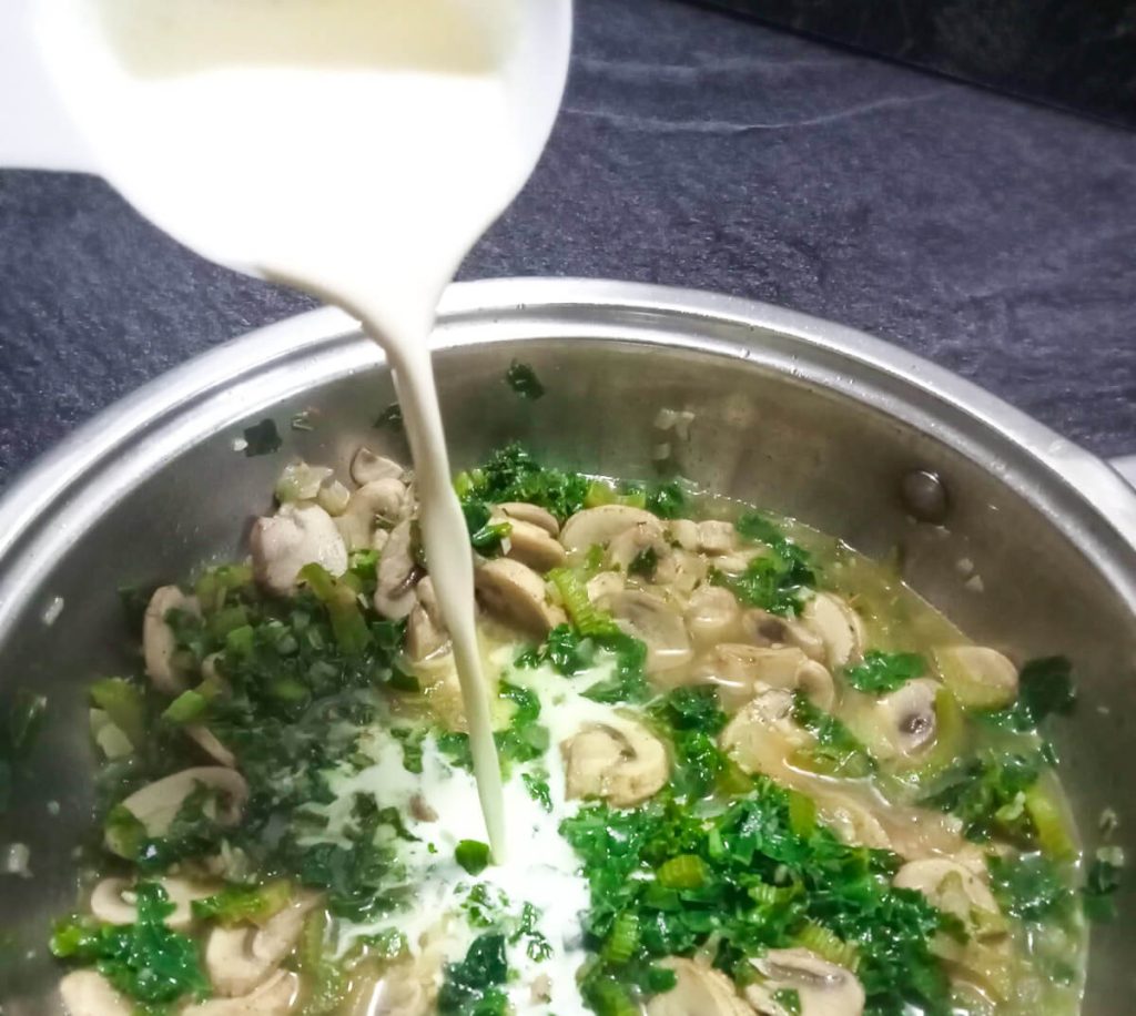 Process photo- adding cream to the mushroom and kale soup.