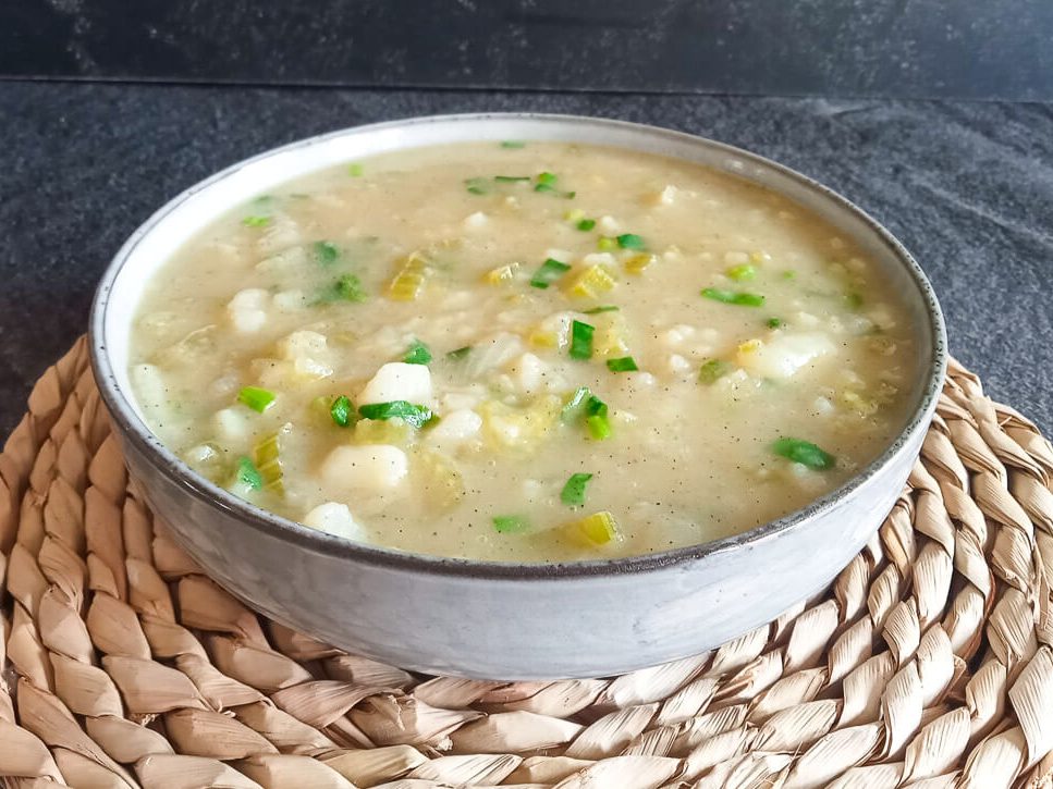 a bowl of leek celery soup on a black background.