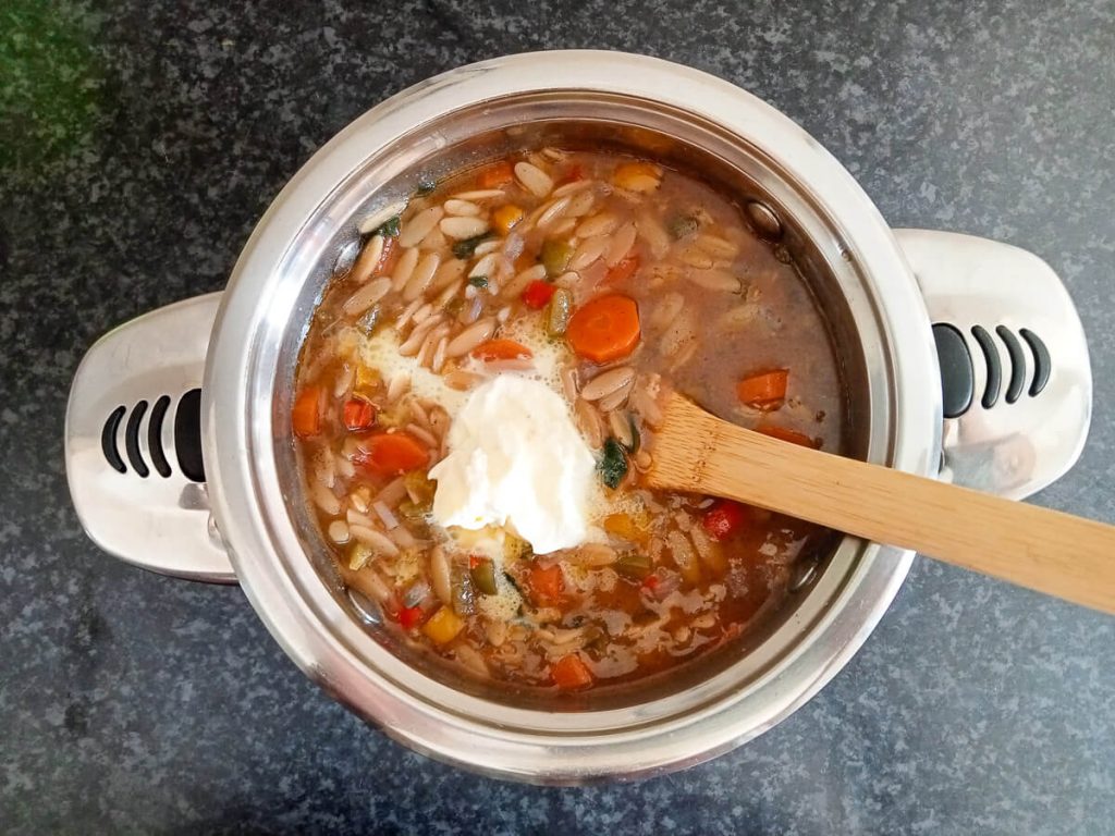 Process photo adding cream to the orzo soup