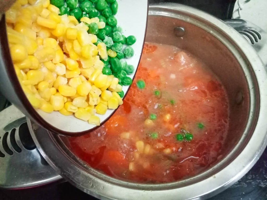 process image: Adding corn and peas into the pot of soup