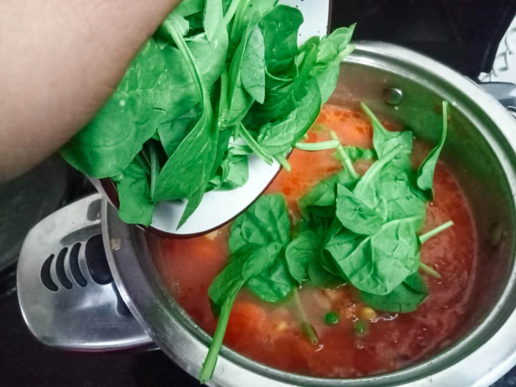 process image: Adding baby spinach into the pot of high-protein soup