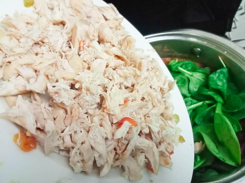 process image: Adding shredded chicken into the pot of soup