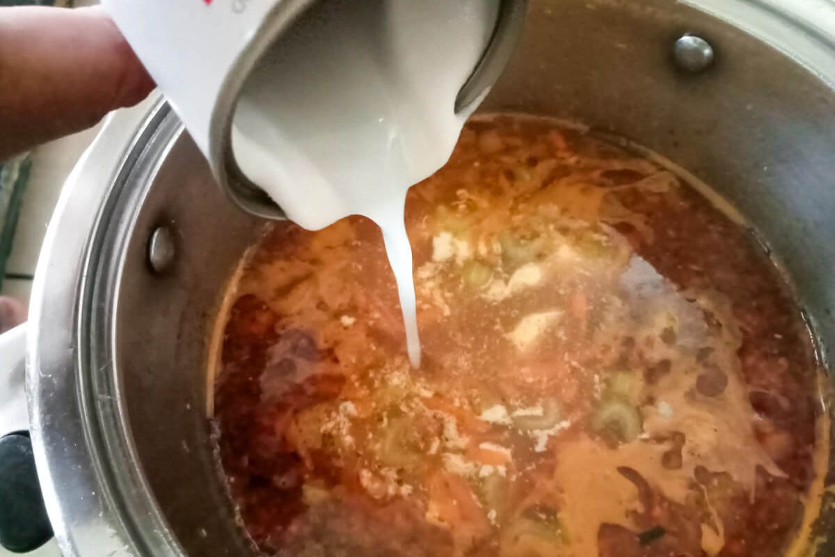 process image: adding coconut milk to the pot of soup