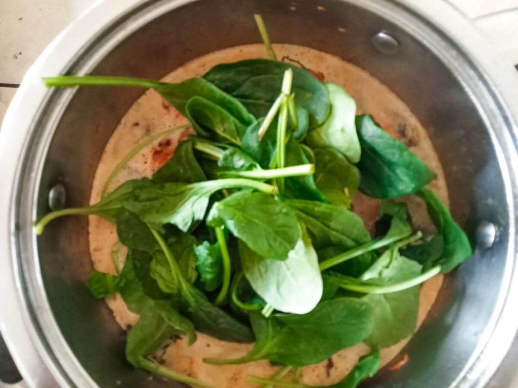 Process image: Adding spinach to the meatball soup