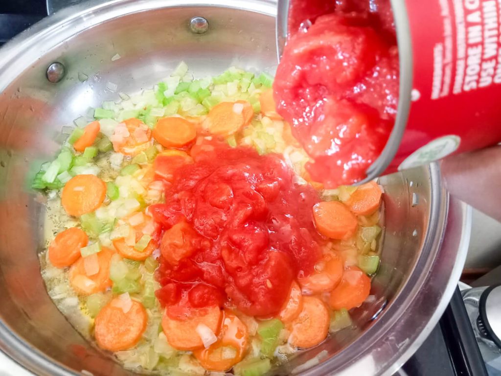 process image: adding canned tomatoes to the pot