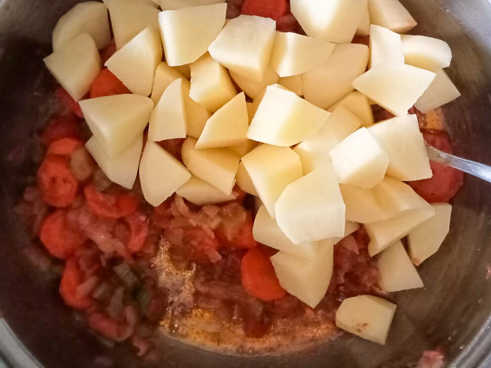 process image: adding potatoes to the pot of soup