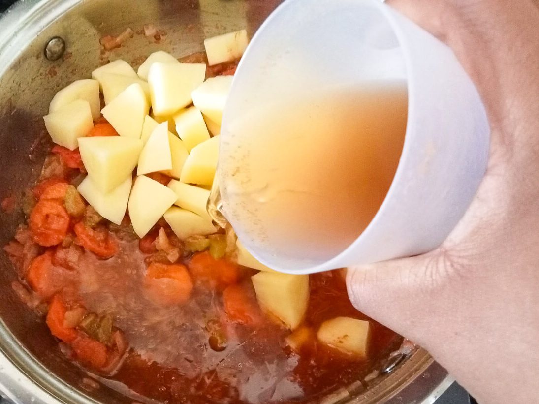 process image: adding bone broth to the pot of soup